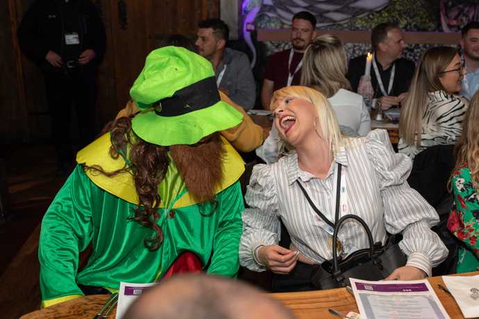 woman laughing with a leprachaun in an irish pub
