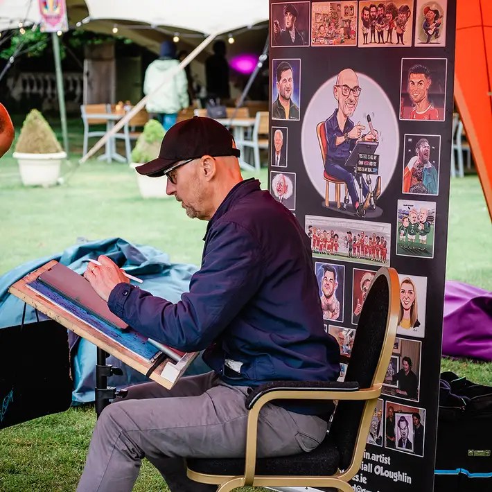 live caricature artist entertaining guests at outdoor corporate team building event in Ireland