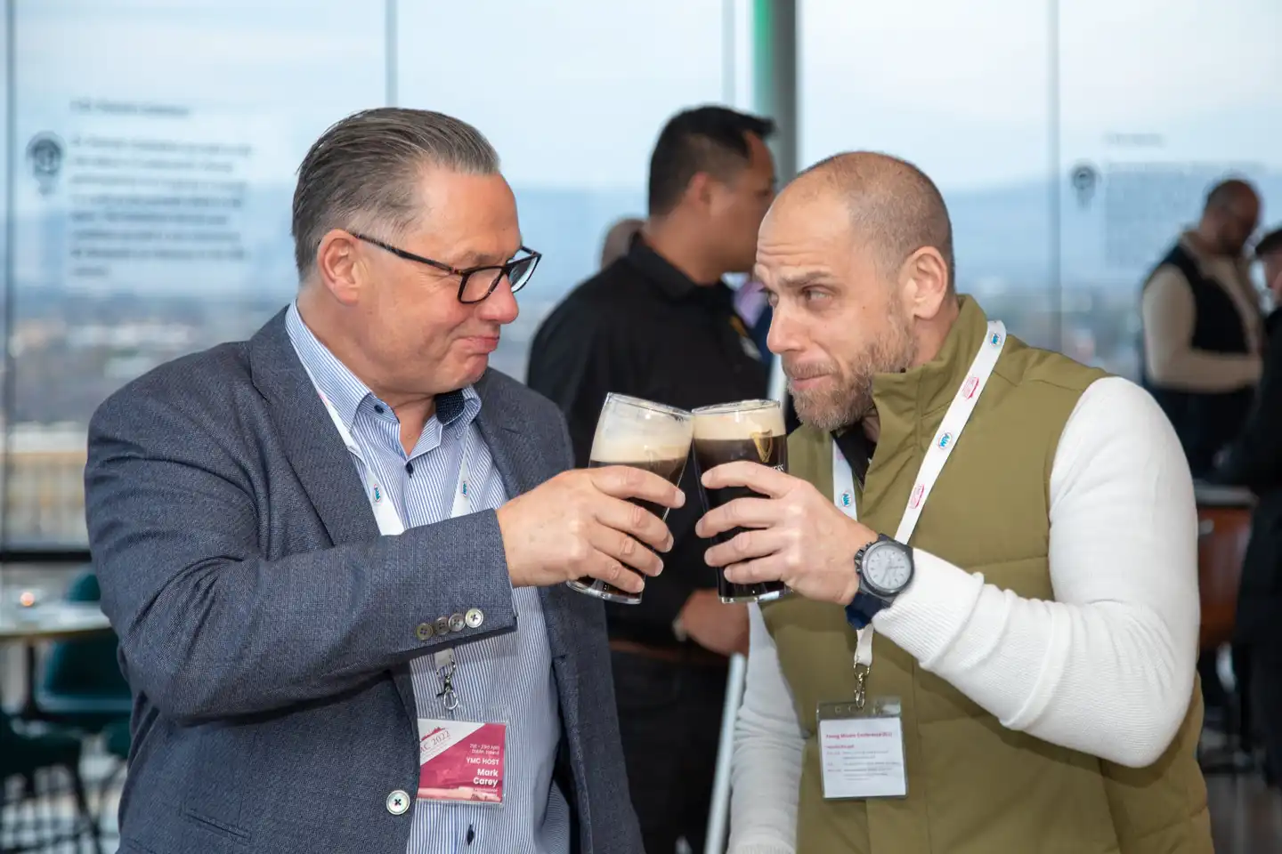 two professionals toasting with pints of Guinness, smiling and engaged in conversation