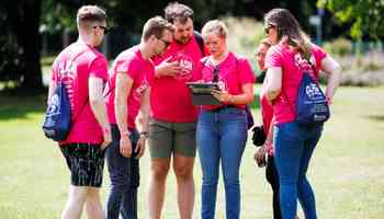 Corporate team using an app during a digital treasure hunt in Dublin smiling and celebrating together outdoors
