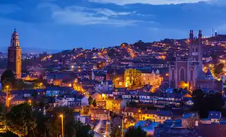 Overview photo of cork at night time with lights and building