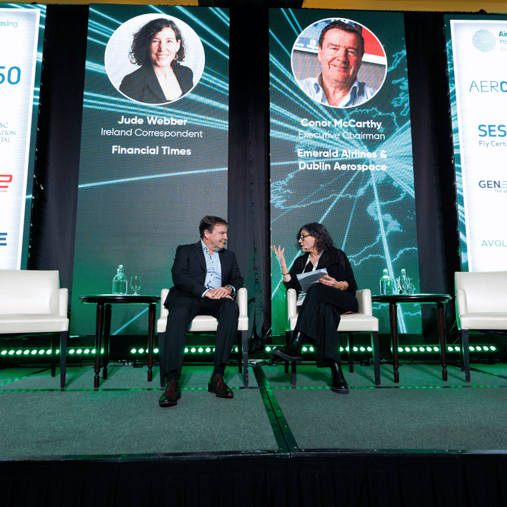 Jude Webber and Conor McCarthy talking together as a panel up on stage sitting on couch chairs