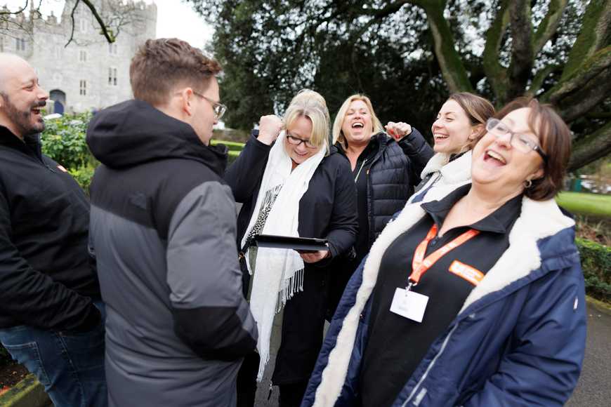 Group of colleagues laughing and celebrating a task completed in a digital team-building challenge