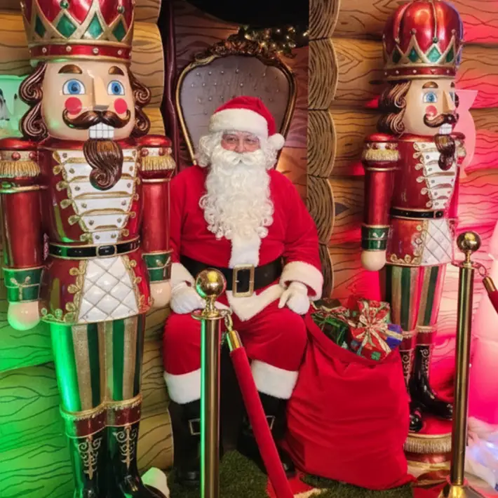 Santa Claus in a festive Christmas grotto surrounded by nutcracker decorations and gifts at a corporate family day event in Ireland organised by Dynamic Events.