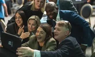 Corporate team laughing and taking a group selfie during a high energy indoor team building activity in Ireland