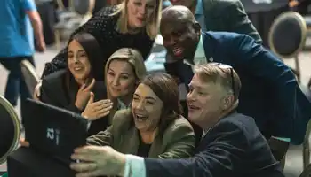 Corporate team laughing and taking a group selfie during a high energy indoor team building activity in Ireland