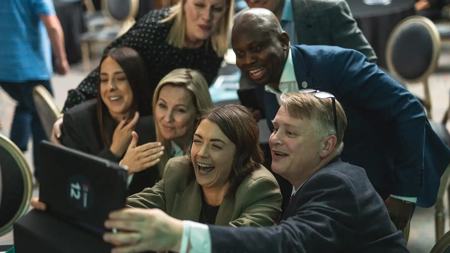Corporate team laughing and taking a group selfie during a high energy indoor team building activity in Ireland