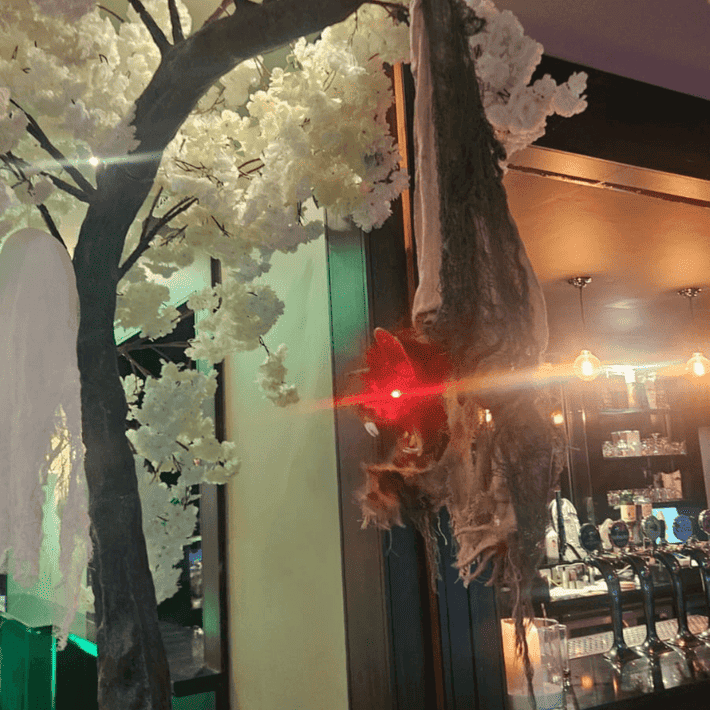 Bat decoration hanging from a tree with red eyes lighting up