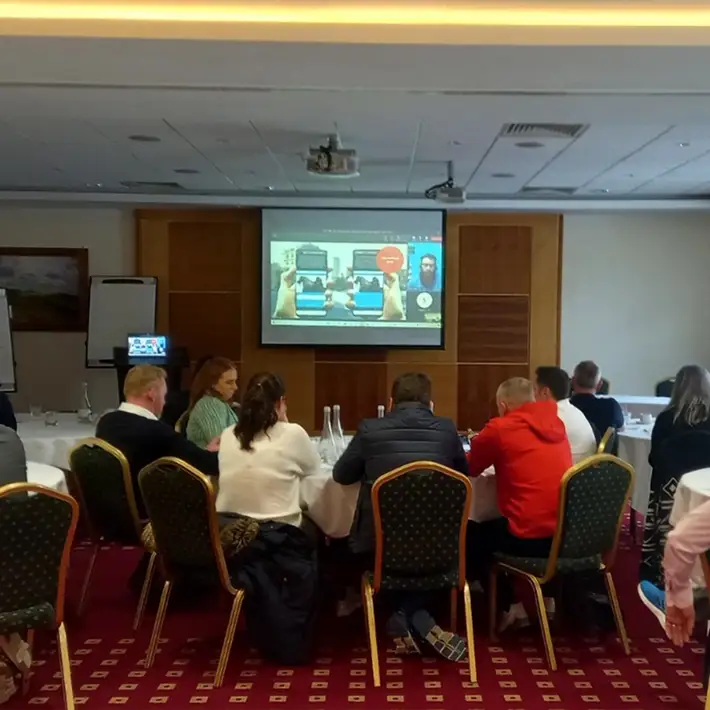 Team in conference room playing a remote hosted digital treasure hunt with live video briefing