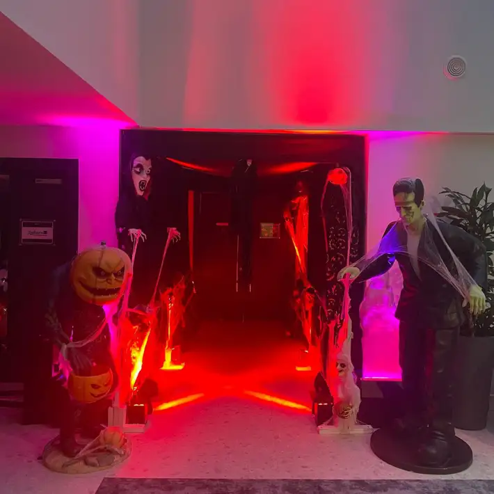 Halloween themed company family day with Frankenstein and pumpkin characters welcoming guests at corporate event entrance.