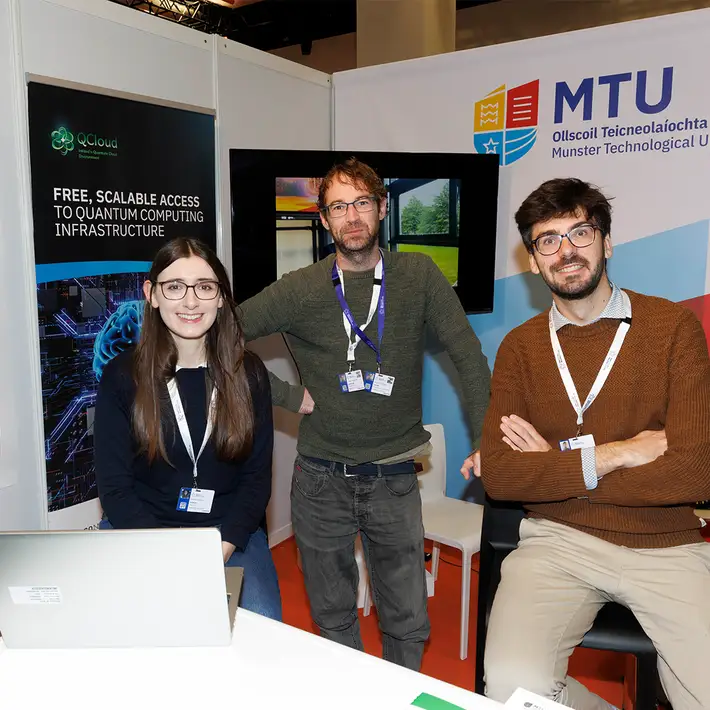 Three researchers at the Munster Technological University exhibition stand showcasing quantum computing research at the NCSC Cyber Expo.