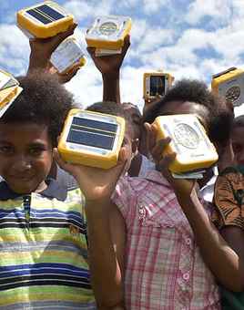 Children holding SolarBuddy lights distributed through corporate sustainable team building initiative