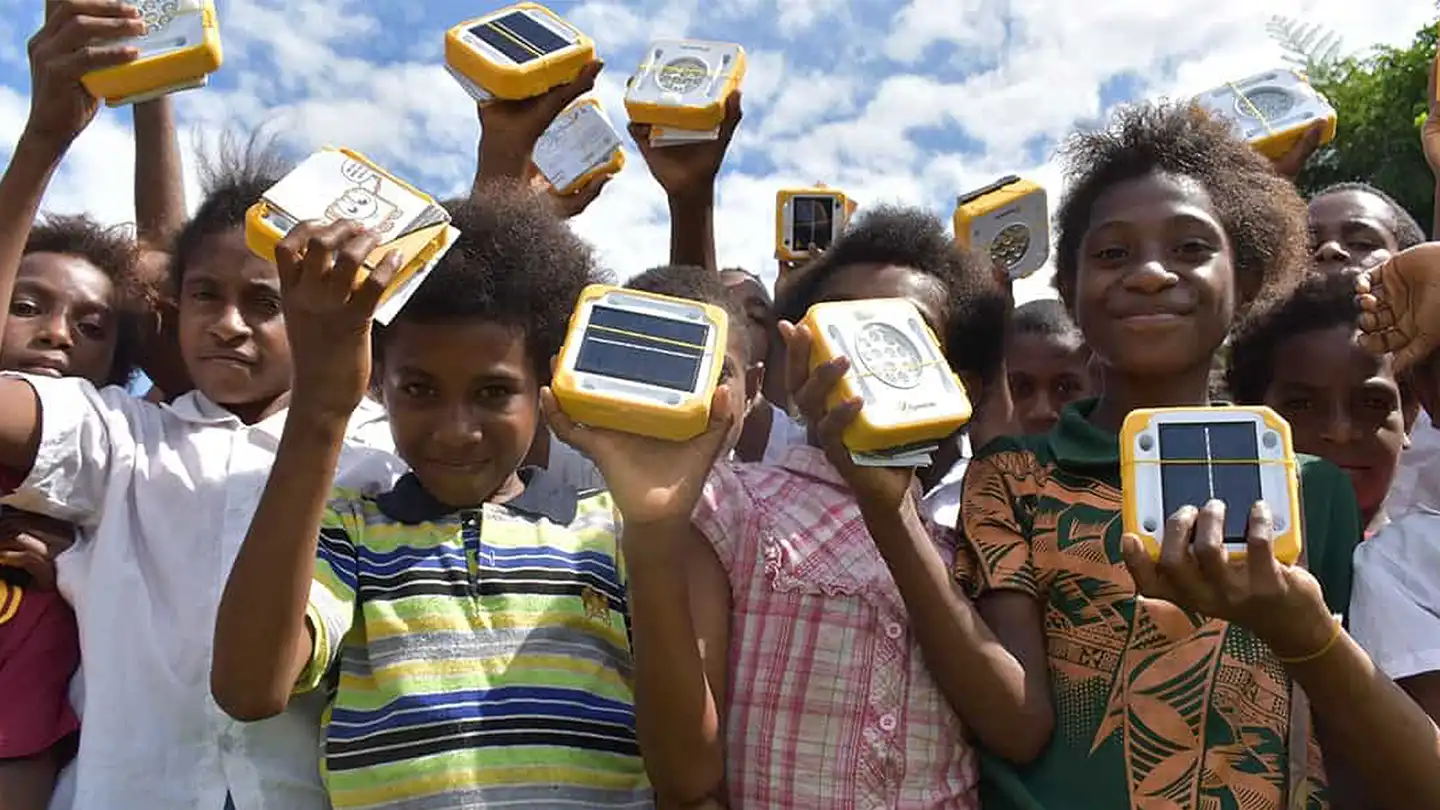 Children holding SolarBuddy lights distributed through corporate sustainable team building initiative