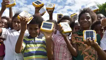 Children holding SolarBuddy lights distributed through corporate sustainable team building initiative