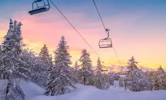 Snowy ski lift at sunrise surrounded by pine trees, representing the winter setting of the Murder on the Slopes virtual team building game in Ireland.