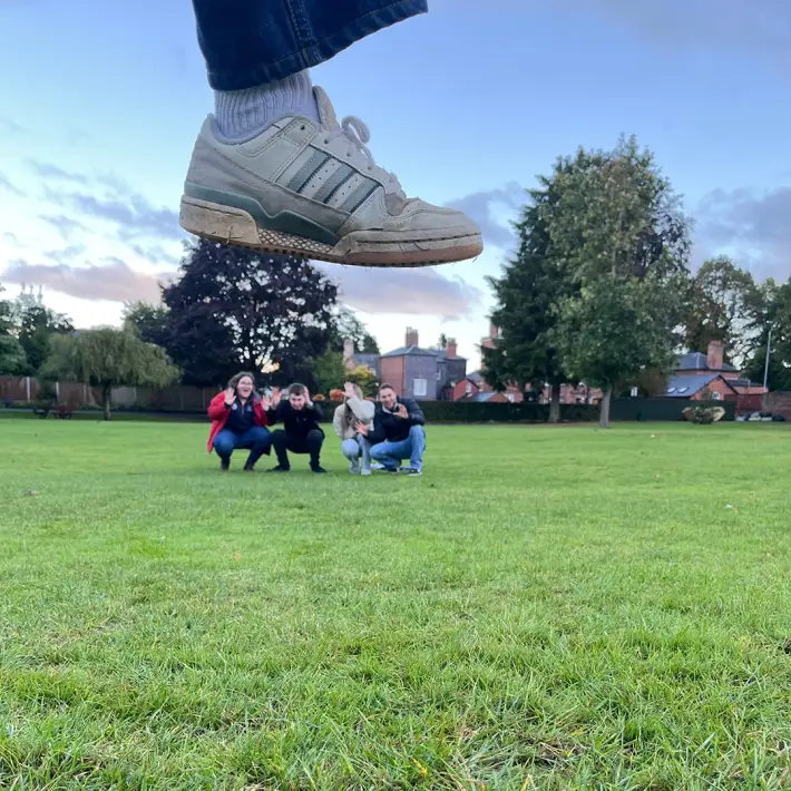 ABP Food Group graduates completing a creative photo task during a multi location digital treasure hunt, using forced perspective to make a giant shoe effect.