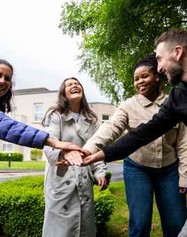 Onboarding team building activity with graduates collaborating outdoors on a sunny day.