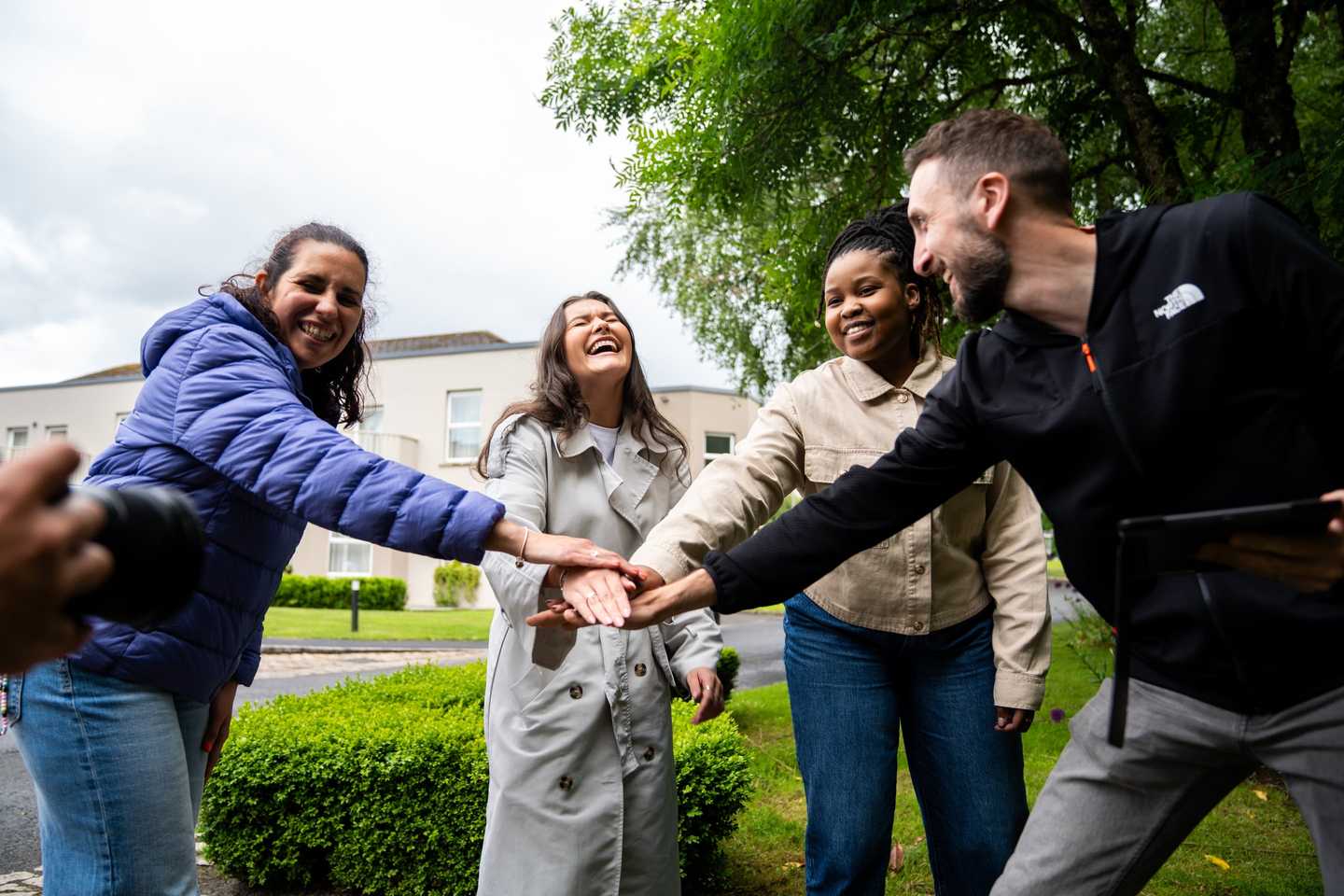 Corporate team building activity in Ireland with colleagues smiling and joining hands outdoors during an August team event.