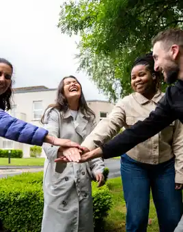 Onboarding team building activity with graduates collaborating outdoors on a sunny day.