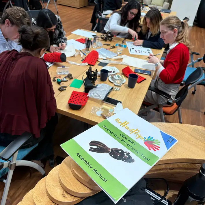 Close up of The Hand Project assembly manual with participants collaborating at a CSR team building workshop in Ireland.