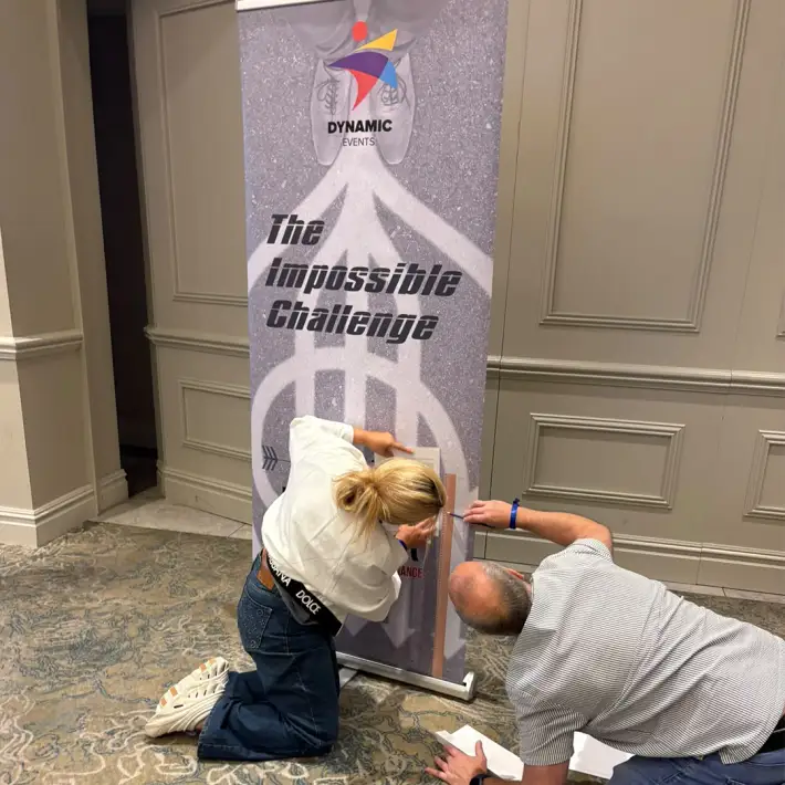 Two Resmed PEI participants working together on the Impossible Challenge activity during their indoor team-building session.