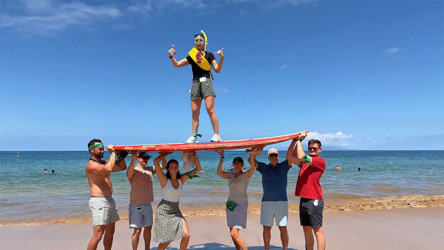Team balancing on surfboard during digital treasure hunt team building activity in Hawaii