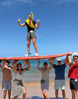 Team balancing on surfboard during digital treasure hunt team building activity in Hawaii