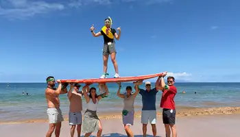 Team balancing on surfboard during digital treasure hunt team building activity in Hawaii
