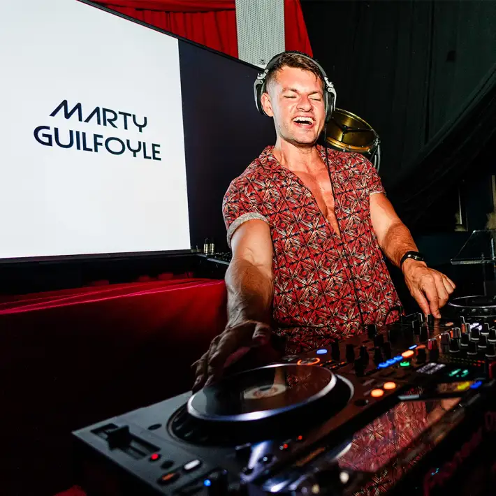 Professional DJ performing at a corporate celebration party with a lively atmosphere and stage lighting in Ireland.