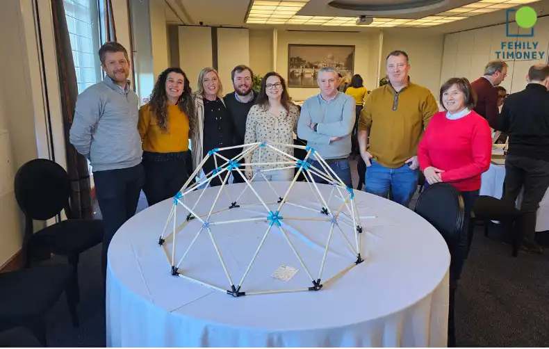 Team members posing in front of a completed domeworks structure, smiling and celebrating.