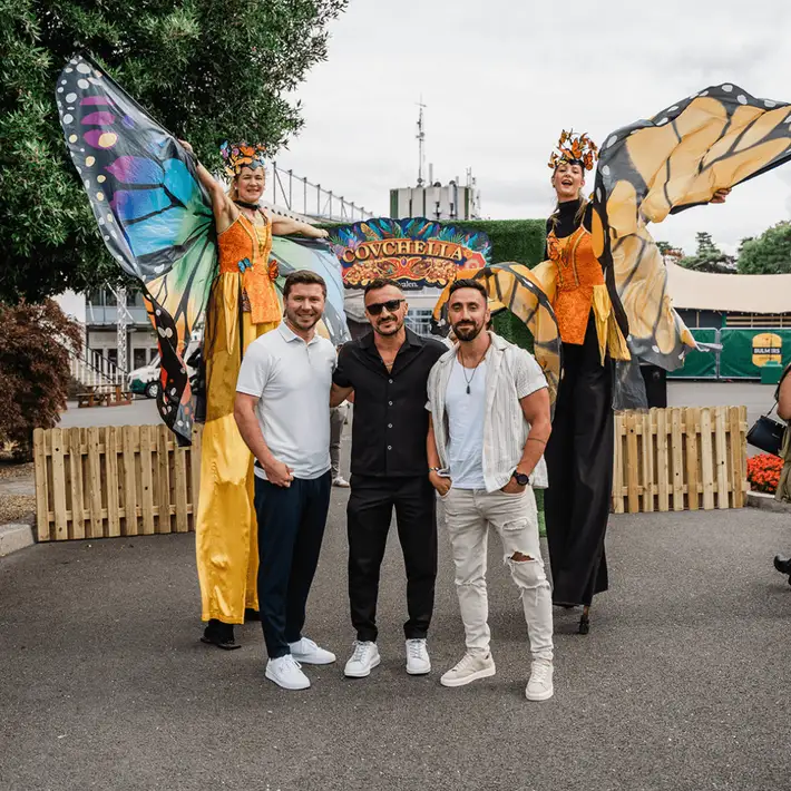 Stilt walkers interacting with guests at corporate festival infront of welcome archway