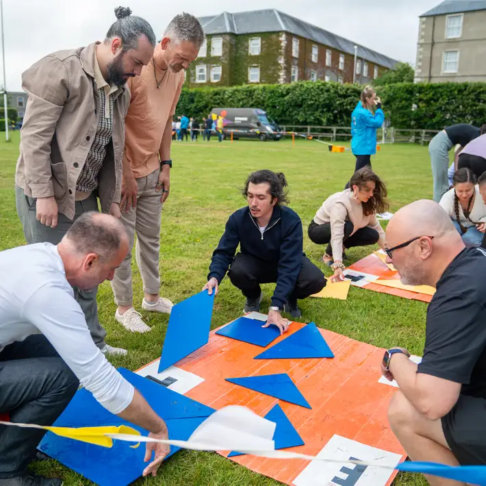 Corporate team solving a giant tangram puzzle during The Challenger outdoor team building activity in Ireland