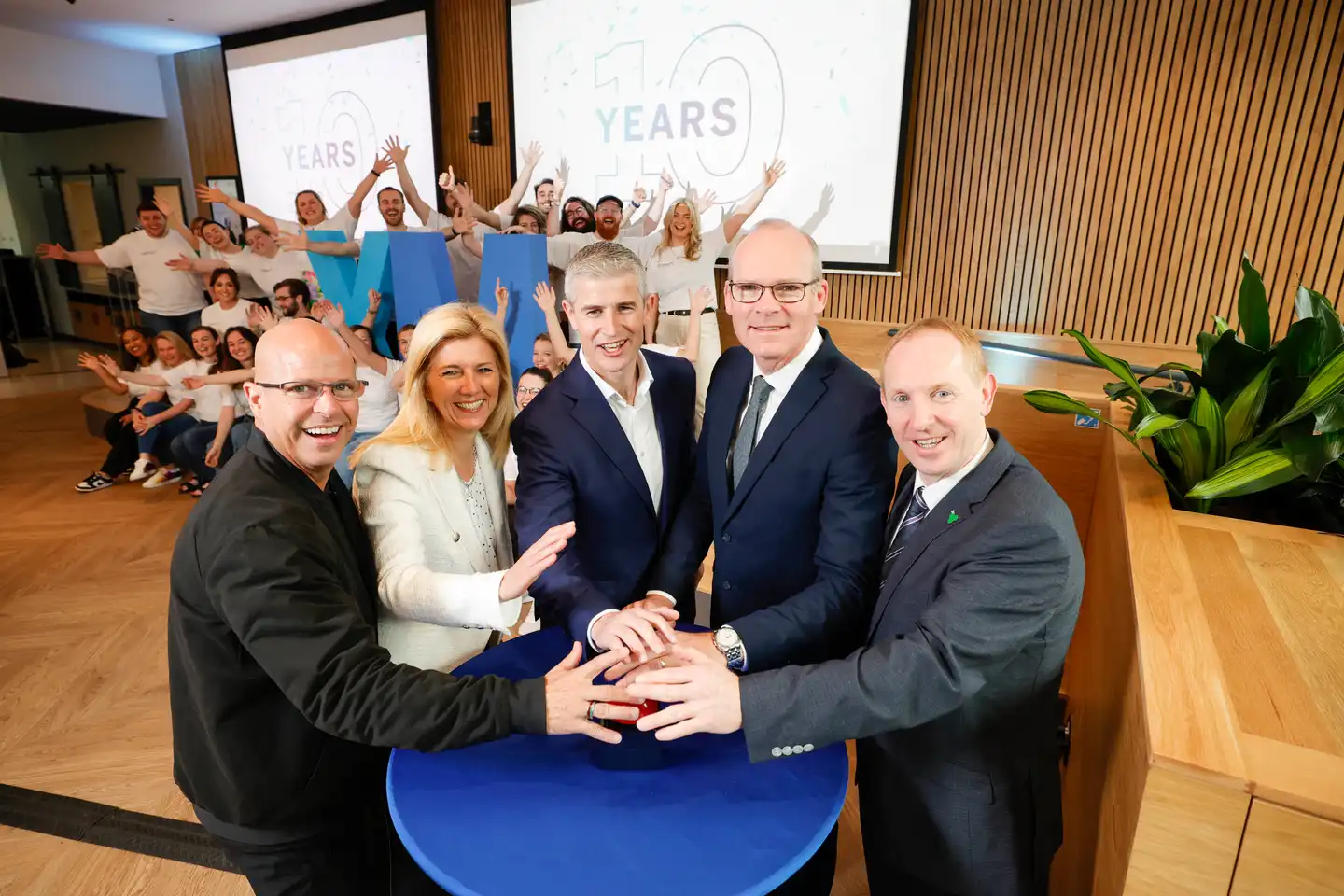 Corporate offsite event with Irish business leaders celebrating 10 year anniversary surrounded by team members at a modern venue in Ireland