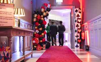 people walking through an alice and wonderland hallway 