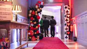 people walking through an alice and wonderland hallway 