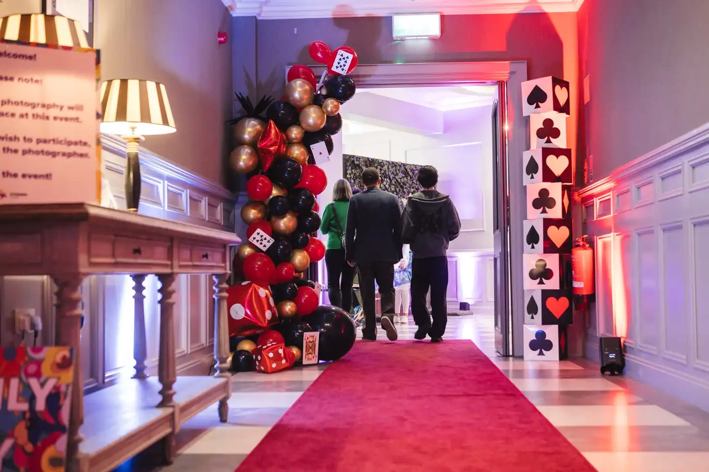 people walking through an alice and wonderland hallway 