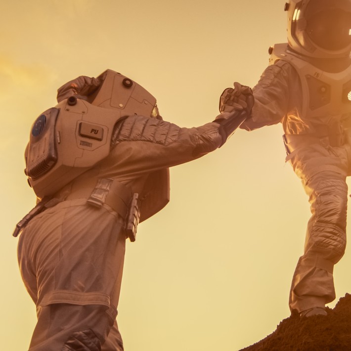 two astronauts helping each other