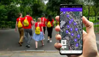 Corporate team building activity outdoors with employees walking to locations and solving app-based digital treasure hunt challenges on a mobile device