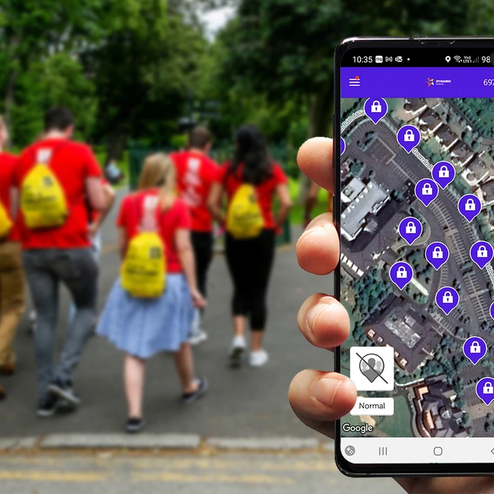 Corporate team building activity outdoors with employees walking to locations and solving app-based digital treasure hunt challenges on a mobile device