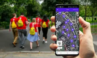 Corporate team building activity outdoors with employees walking to locations and solving app-based digital treasure hunt challenges on a mobile device