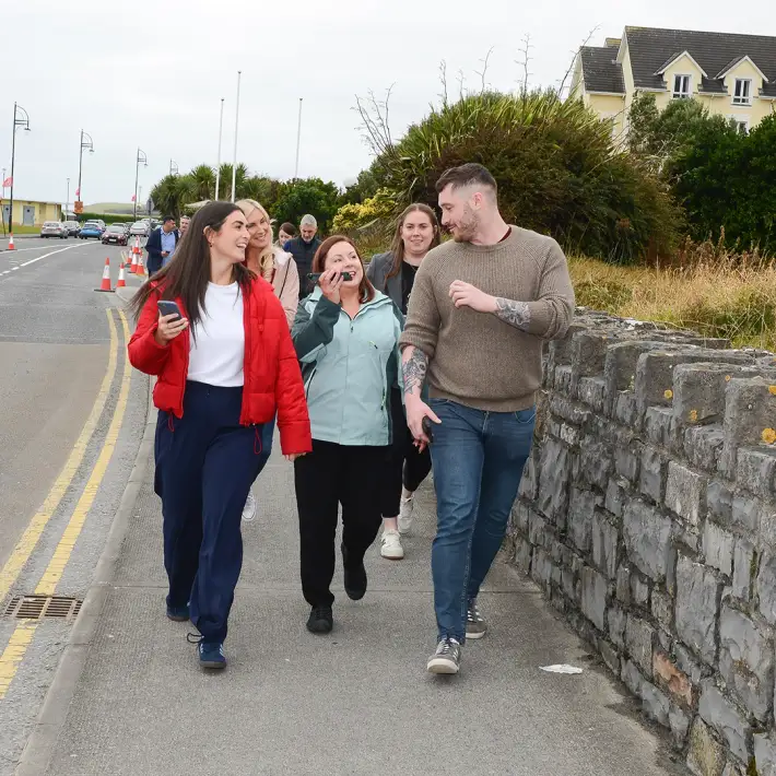 Employees walking and laughing along the promenade during a Digital Treasure Hunt in Galway