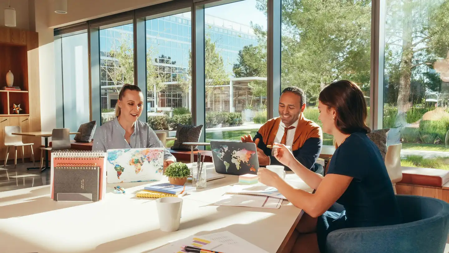 Woman in Blue Shirt Sitting Beside Woman in Red Shirt working on laptops during team building
