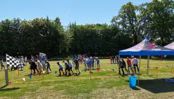 College staff taking part in an outdoor team building challenge with Dynamic Events, featuring group activities, colourful bunting, and branded tents on campus grounds in Ireland.