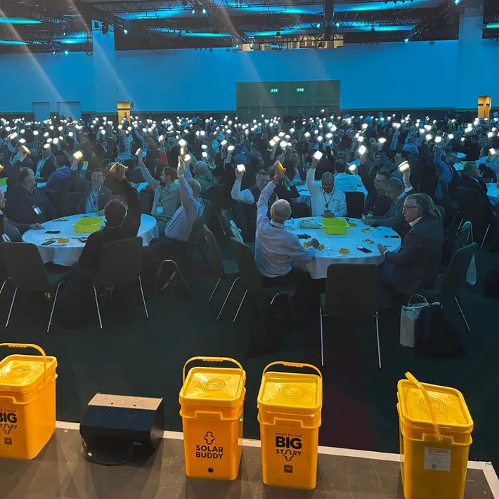 Attendees raise their completed SolarBuddy lights, creating a striking illuminated moment during the event’s closing.