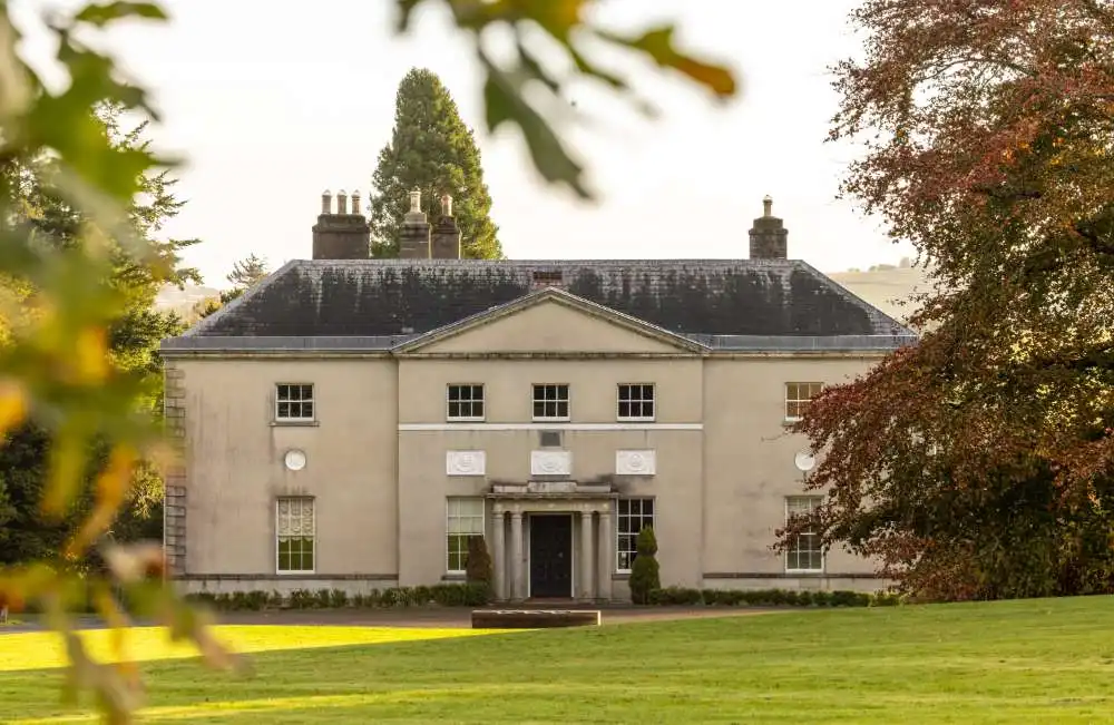 Avondale House pictured through the trees on a plain of grass
