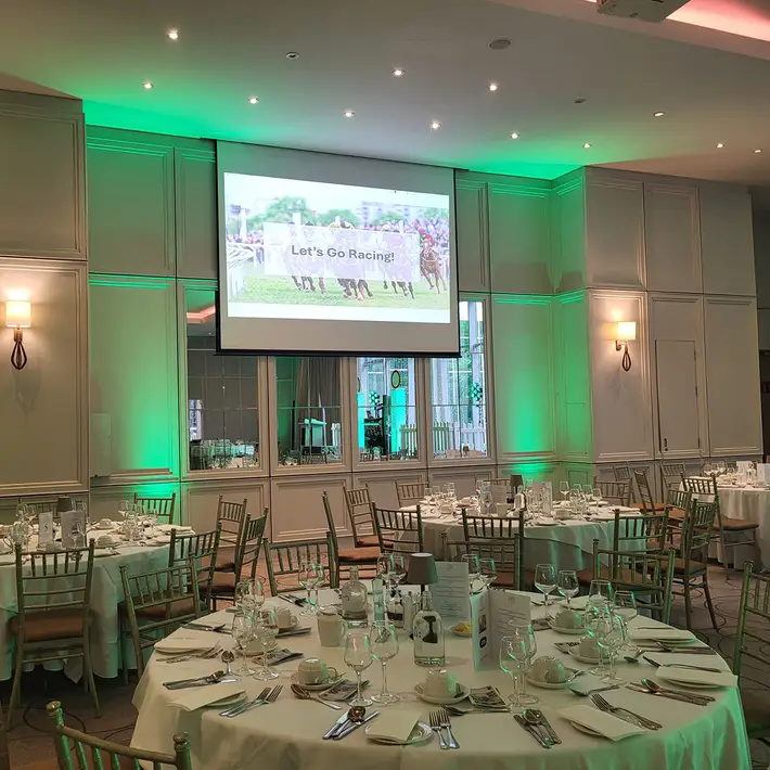 Corporate Race Night venue setup with horse racing displayed on a large projection screen