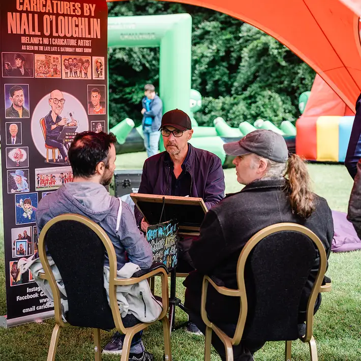 caricature team building workshop with Niall O’Loughlin drawing guests at outdoor corporate event in Ireland
