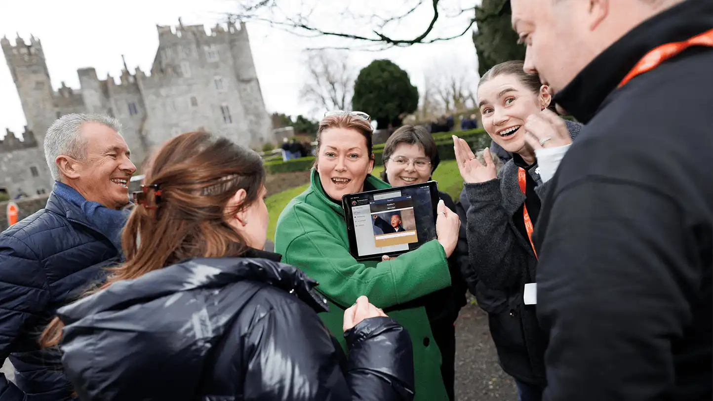 Corporate team enjoying a Venue Adventure digital treasure hunt on hotel grounds in Ireland, using an iPad to complete GPS challenges