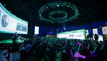 Large audience attending a company kick-off conference in Ireland with keynote speaker on stage, branded screens, and professional event setup by Dynamic Events.