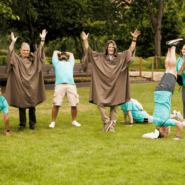 Teams reach actors and pose for a yoga task 